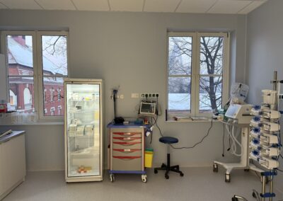 Pomieszczenie medyczne z lodówką, wózkiem i sprzętem medycznym