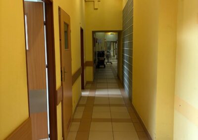 Korytarz szpitalny z żółtymi ścianami i oświetleniem sufitowym